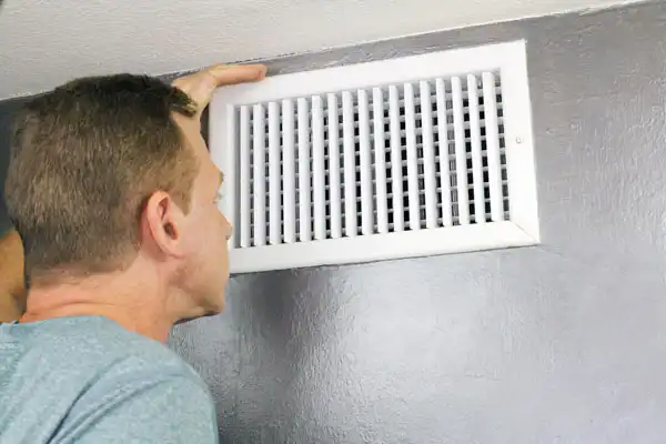 Man inspecting a wall vent.